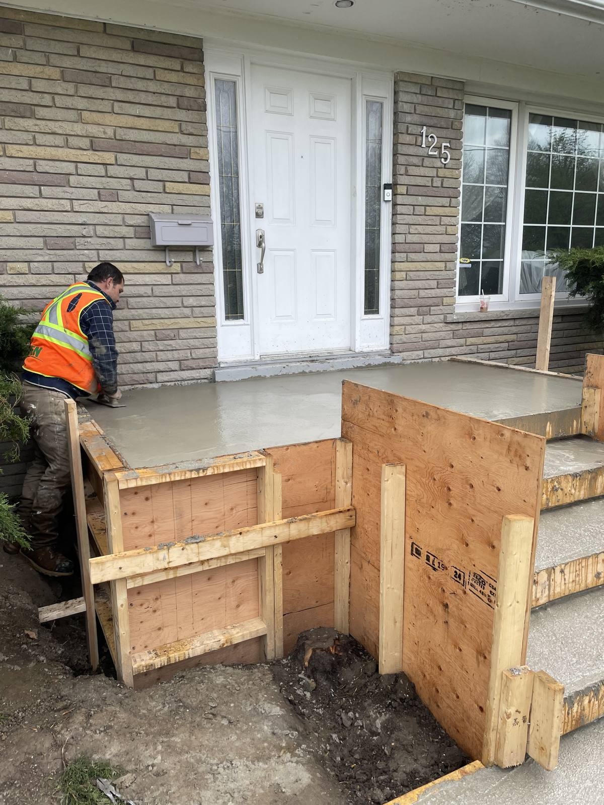 Berm Inc. crew troweling a freshly poured concrete porch and entry steps at an Ontario home