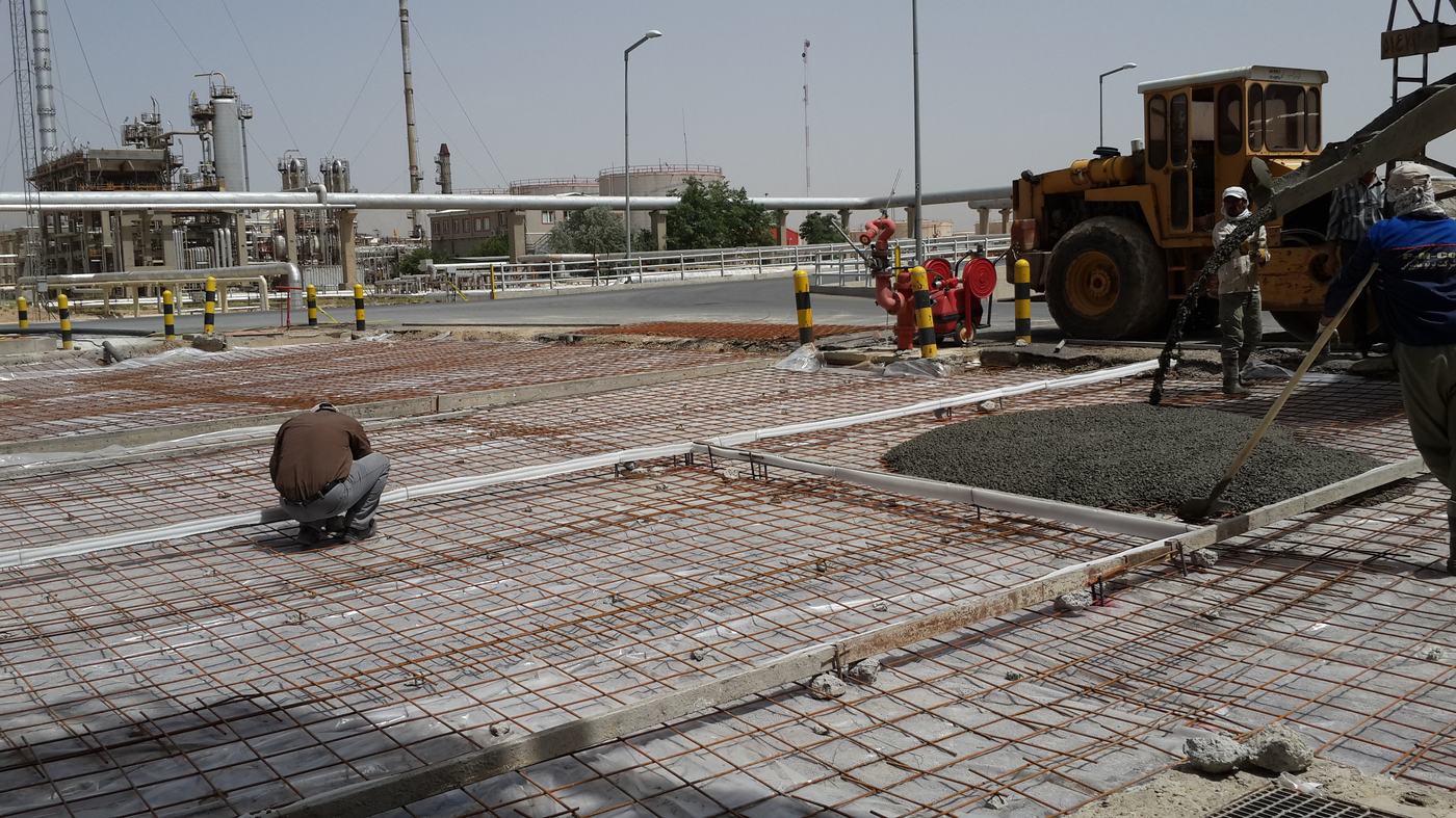 Workers pouring concrete over reinforcing mesh — building science in action