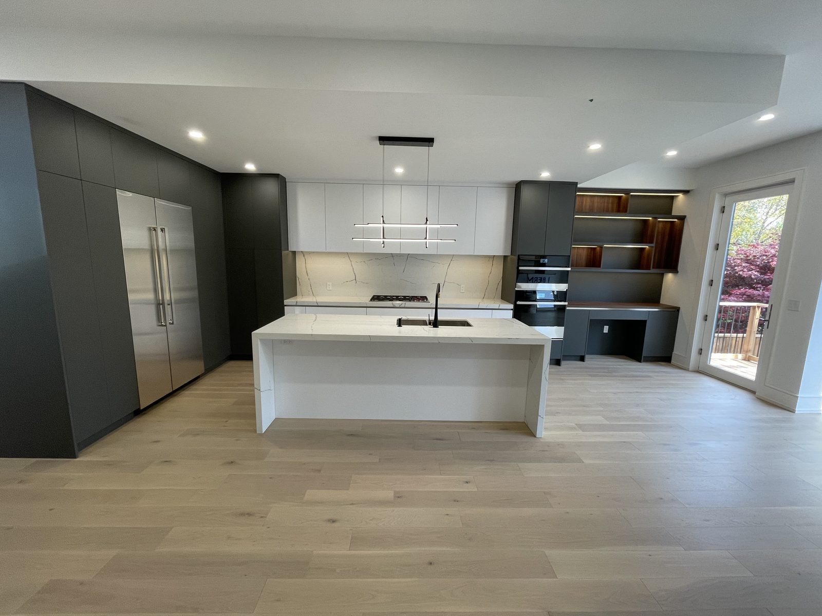 Custom kitchen with charcoal cabinetry and waterfall island — Berm Inc. project photo