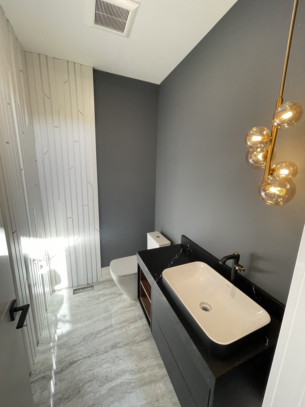 Powder room with floating black vanity and oak slat feature wall — Berm Inc. project photo